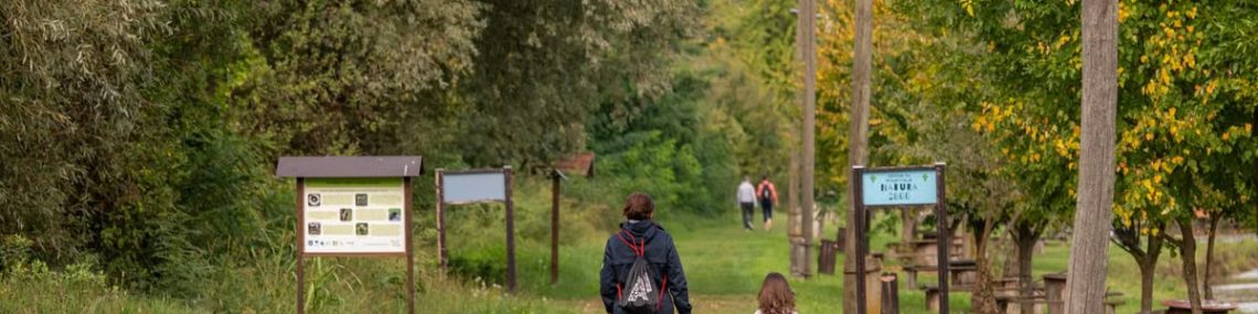 A parent and child walking on a path in a scenic nature reserve in Croatia, surrounded by lush greenery.